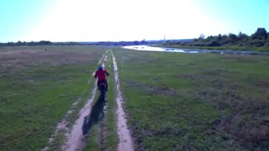 Adam yazın bir spor bisikleti sürüyor. Göl kenarında.