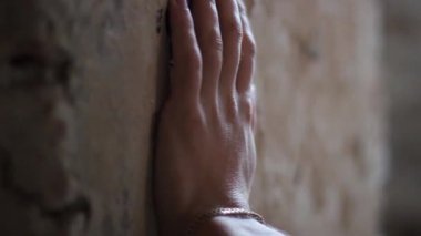 Adam elleriyle duvara dokunuyor.