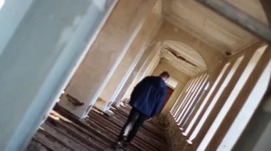 Adam terk edilmiş bir binadan geçiyor.