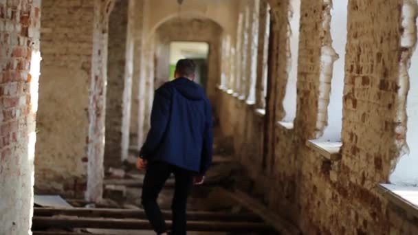 Un tizio cammina attraverso un edificio abbandonato — Video Stock