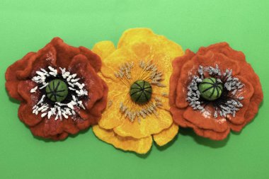 El yapımı keçeli çiçekler, yeşil arka planda üç keçeli çiçek.