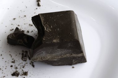 Büyük doğranmış çikolata parçası beyaz bir seramik tabakta yatıyor.