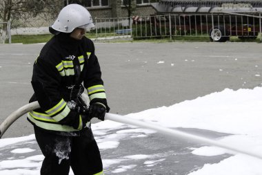 04 24 2019. Divnoye, Stavropol Bölgesi, Rusya. Tarım okulundaki itfaiye teşkilatının kurtarma ekipleri ve itfaiyecilerinin gösterileri. Bir itfaiyecinin köpük kaynağı, köknar.