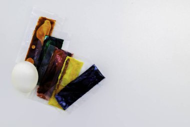 Paskalya hazırlığı, beyaz tavuk yumurtası ve beyaz arka planda yumurtalar için renkli boya torbaları, kopyalama alanı