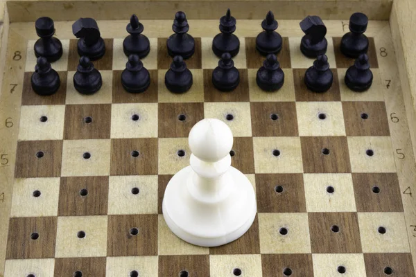 Concepto, pequeñas piezas de ajedrez de madera negro de pie delante de un peón blanco grande — Foto de Stock