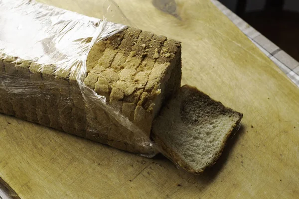 Szeletelt kenyér, külön szelettel a vágódeszkán — Stock Fotó