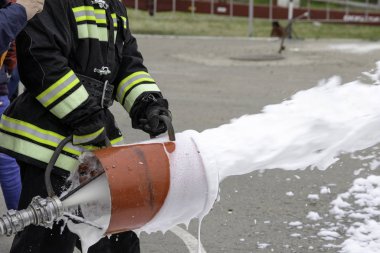 Köpük jeneratöründen köpük tedarik ediliyor. İtfaiyeciyi savaş kıyafetleri içinde tutan köpük jeneratöründen yangın söndürücü sinekler çıkıyor.
