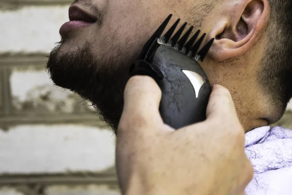 El barbero se corta la barba a un tipo con una máquina de esquilar — Foto de Stock