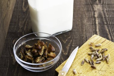 Kocacığım, tarih sütü, geleneksel ramazan yemeği, yemek, malzemeler, bir tabakta oyulmuş hurma, kesme tahtasındaki bıçak ve tohumlar ve ahşap bir masada duran süt.