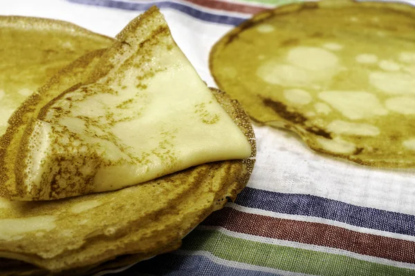 Ready-made rosy pancakes lie on a napkin on a table — Stock Photo, Image