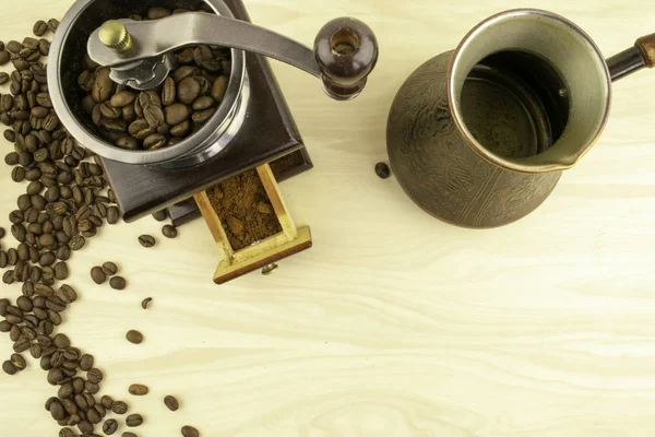 Granos de café, molinillo de café manual y un turco para preparar café están sobre la mesa —  Fotos de Stock