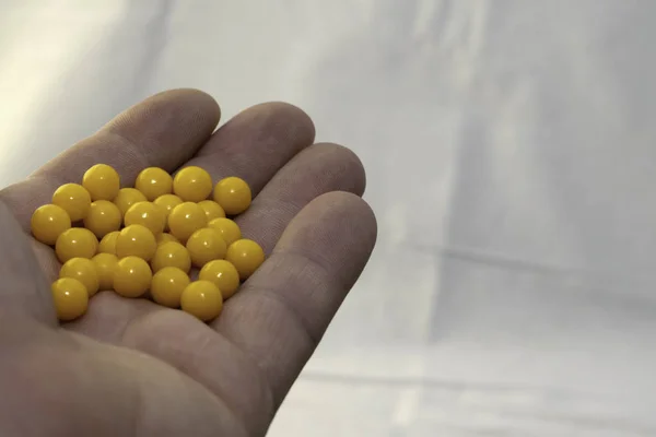 hand holding a handful of yellow pills