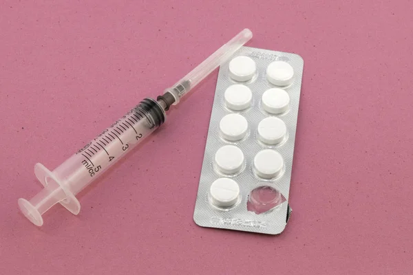 Pillen und Spritze auf rosa Samthintergrund — Stockfoto