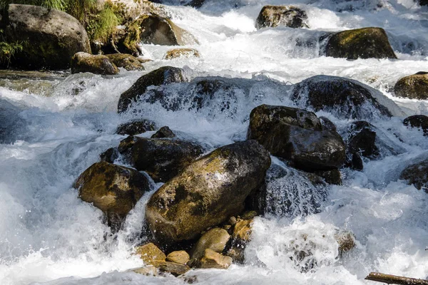 L'acqua del burrascoso fiume di montagna che scorre tra sassi e massi — Foto Stock