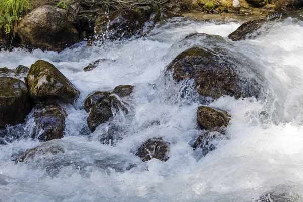 L'acqua del burrascoso fiume di montagna che scorre tra sassi e massi — Foto Stock