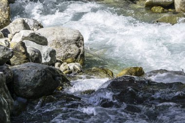 Fırtınalı dağ nehrinin suyu taşların ve kayaların arasında akıyor.