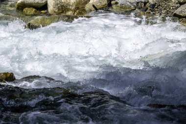 Fırtınalı dağ nehrinin suyu taşların ve kayaların arasında akıyor.