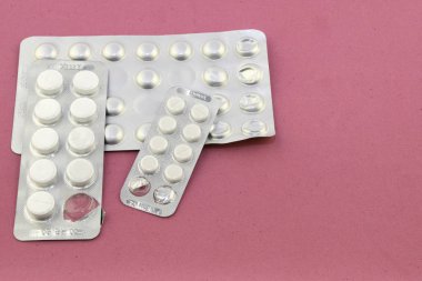 Pembe kadife arka planda üç paket hap.