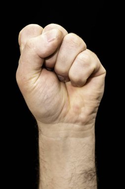 Erkek eli siyah arkaplanda bir yumruğa sıkıştı.