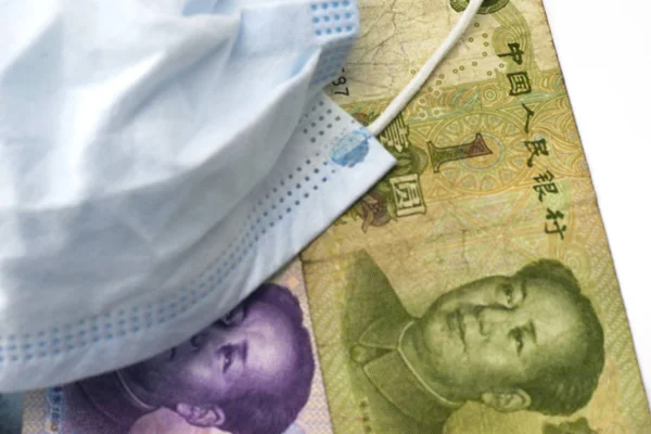 Het concept coronovirus en de economie van China Chinese yuan geld liggen in de buurt van medische hygiëne masker close-up — Stockfoto