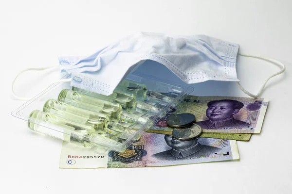 concept coronovirus and Chinese economy, Chinese yuan money, hygiene mask and ampoules with medicine on the white background