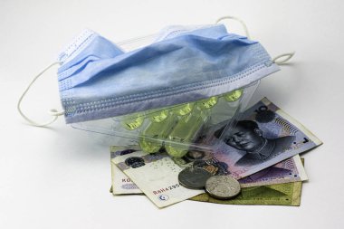 konsept koronovirüs ve Çin ekonomisi, Çin yuanı para, hijyen maskesi ve beyaz arka planda ilaç ampulleri