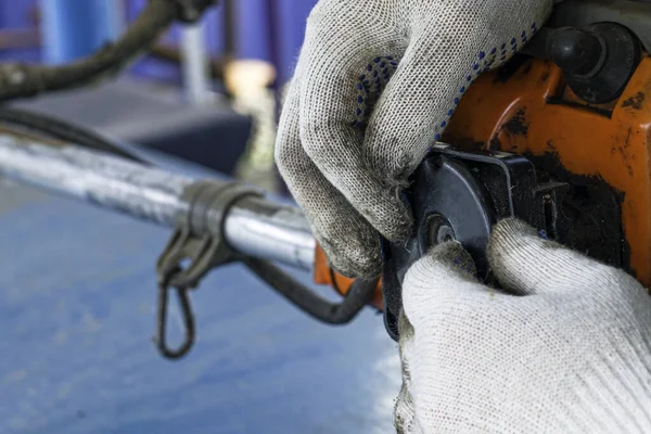 the master in working gloves repairs the engine of the old gas trimmer removes the cover of the air filter