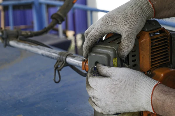 Un maestro en guantes de trabajo repara el motor de la vieja recortadora de gas desenrosca el perno de la cubierta del carburador y el filtro de aire — Foto de Stock
