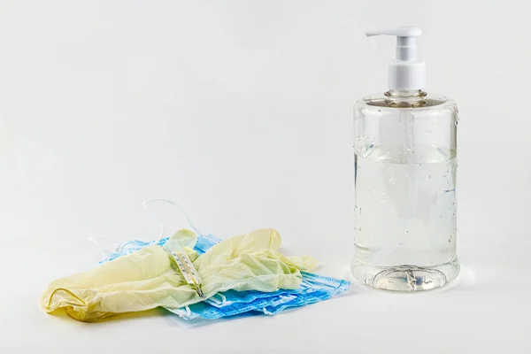 medical protective hygiene masks, rubber gloves, thermometer and a sanitizer in a transparent bottle are on the White background