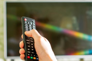 Uzaktan kumanda arka planda bulanık bir erkek televizyonunun elinde.