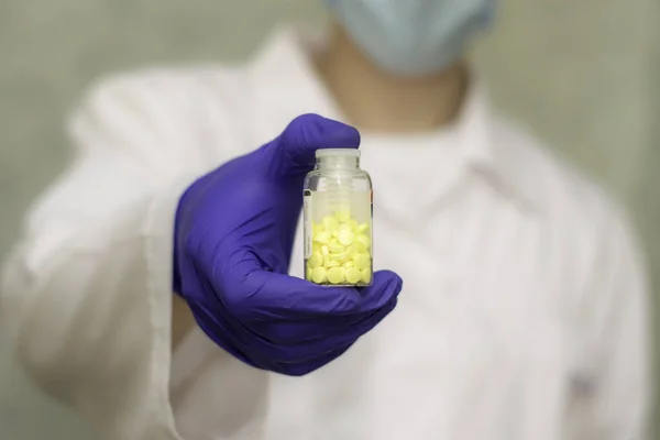 bubble with yellow pills in the doctor s hand. doctor in the background in blur