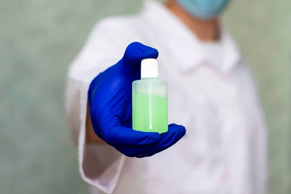 bubble with a green sanitizer in the doctor's hand against the background of the doctor in blur