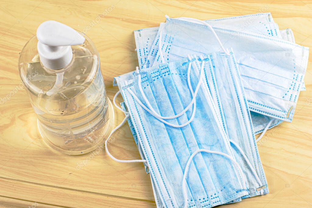 sanitizer in a bottle and blue medical hygiene masks lie on the table