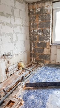 Döşemeleri sökülüp, su ve drenaj borularına maruz bırakılan eski bir banyonun yıkılması.