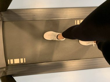 Koşu bandında koşan kadın ayağı.