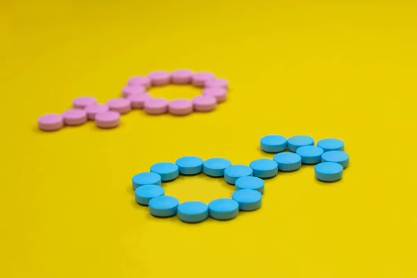 Μπλε χάπια με τη μορφή σημαδιών φύλου του Άρη και της Αφροδίτης σε κίτρινο φόντο. Ιατρική έννοια. — Φωτογραφία Αρχείου