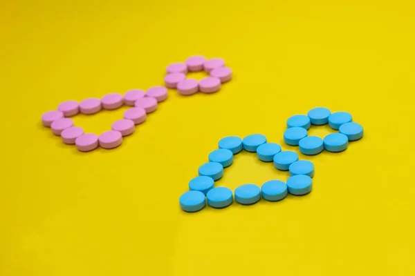 Male and female symbols made from pink and blue pills on yellow background. — 스톡 사진