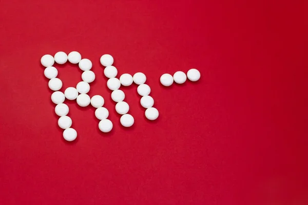 Factor Rh negativo. Rh- inscripción hecha de píldoras blancas sobre un fondo rojo con espacio de copia . Imagen De Stock