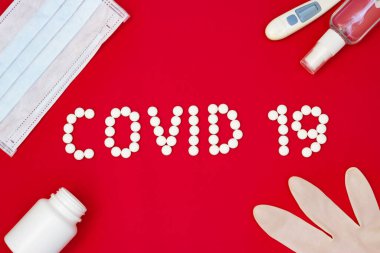 Kırmızı arka planda ilaç, el antiseptiği, termometre ve koruyucu maskeli Covid 19 metni. Roman Coronavirus 2019-nCoV, MERS-Cov Orta Doğu Solunum Sendromu Coronavirüsü.