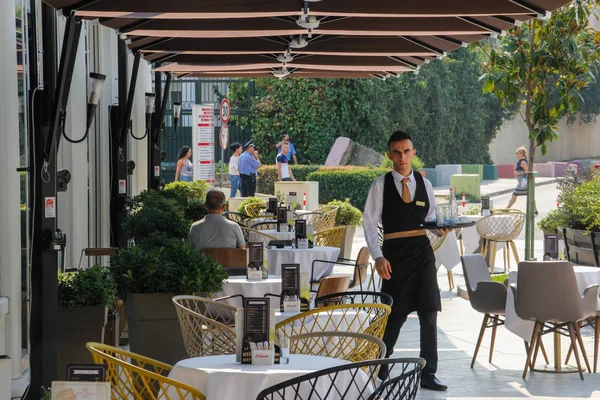 Tiran, Arnavutluk - 20 Ağustos 2017: Arnavutluk 'un başkenti Tiran' da masalarda ve garsonların oturduğu güzel ve rahat bir kafe. Arnavut mutfağı