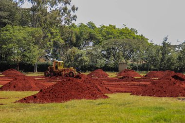 Kenya, Nairobi 'de bir traktörle tarlada parlak, doymuş ve yağlı kırmızı toprak yığınları..