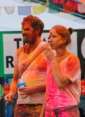 Pokhara, Nepal - 14 Nisan 2014: Holi festivalinde çok renkli boyalı genç bir çift. Kız sigara içiyor..