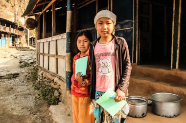 Besisahar, Nepal - 18 Mart 2014: Himalaya dağlarındaki fakir Nepalli kızlar, gönüllü yardımdan Nepal 'deki çocuklara kadar ellerinde okul notları ve kalemleri tutuyorlar..