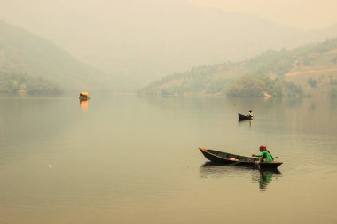 Pokhara, Nepal - 12 Mart 2014: Gün batımında sakin ve sessiz olan Feva Gölü, Pokhara şehrinin en önemli şehridir. Nepal 'in doğası. Balıkçılarla birlikte gölde basit ahşap balıkçı tekneleri..