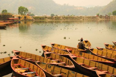 Pokhara, Nepal - 12 Mart 2014: Gün batımında sakin ve sessiz olan Feva Gölü, Pokhara şehrinin en önemli şehridir. Basit ahşap balıkçı tekneleri kıyıya bağlıdır..