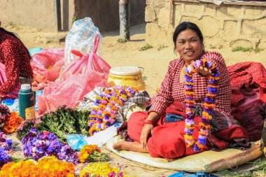 Katmandu, Nepal - 8 Nisan 2014: Zarif sarili Nepalli kadın satıcı Katmandu sokak pazarında çiçek çelengi satıyor.