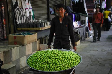 Shiraz, İran - 17 Mayıs 2017: Genç İranlı bir adam pazarda küçük yeşil elmalar satıyor.