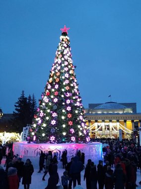 Şehirde yeni yıl oyuncakları ve çelenkleri olan ağaç ve insanlar