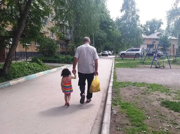 一个男人和一个小女孩从后面沿着大路走着 — 图库照片