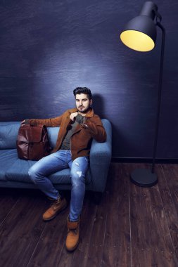 Kanepede oturan yakışıklı adam.